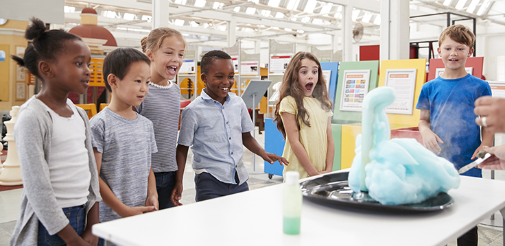 Kids standing around a table with a foam experiment on it.