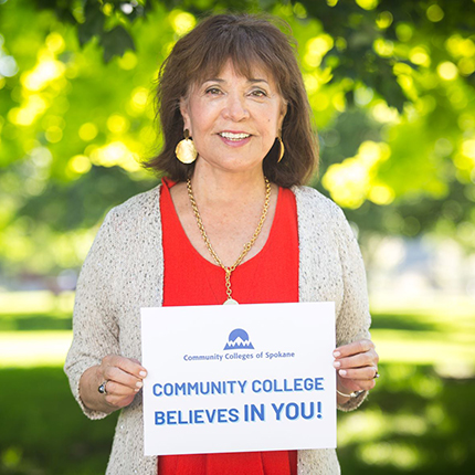 Chancellor Christine Johnson holding a sign that says "Community College Believes in You!"
