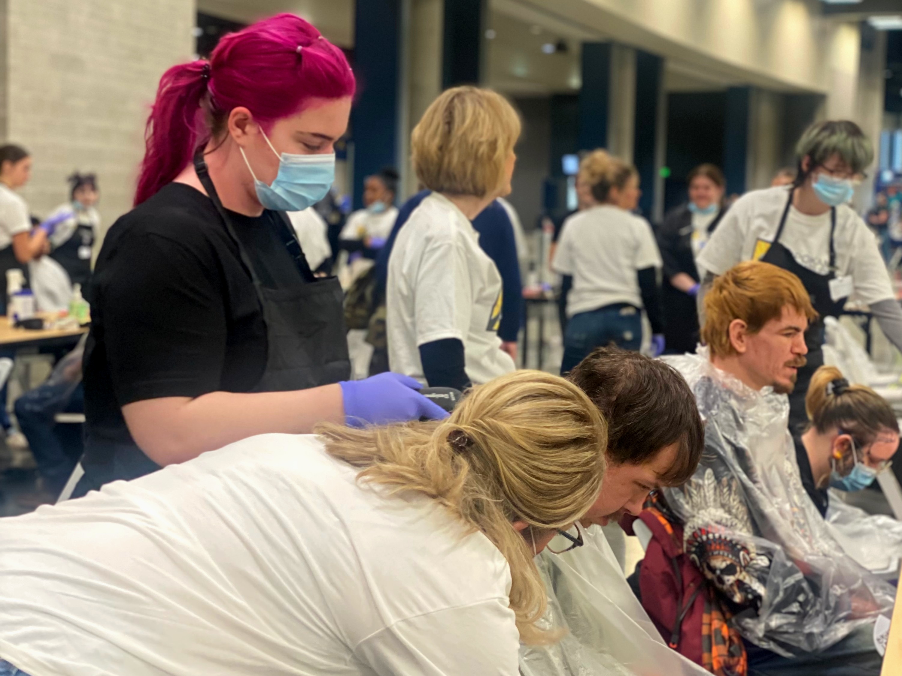 SCC cosmetology students administering haircut to Homeless Connect attendee. 